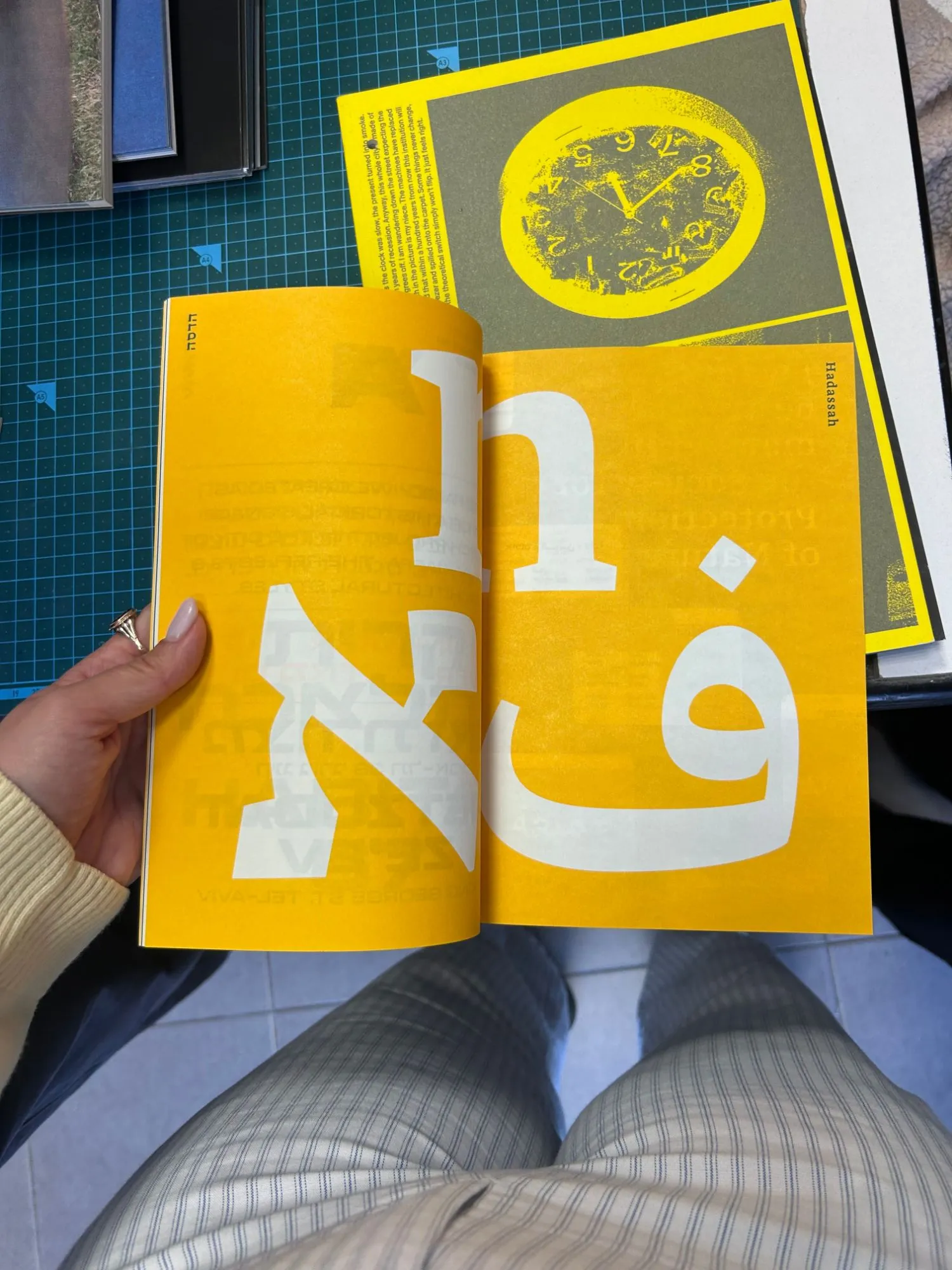 A yellow risograph booklet held open on facing pages of Hebrew and Arabic letterforms