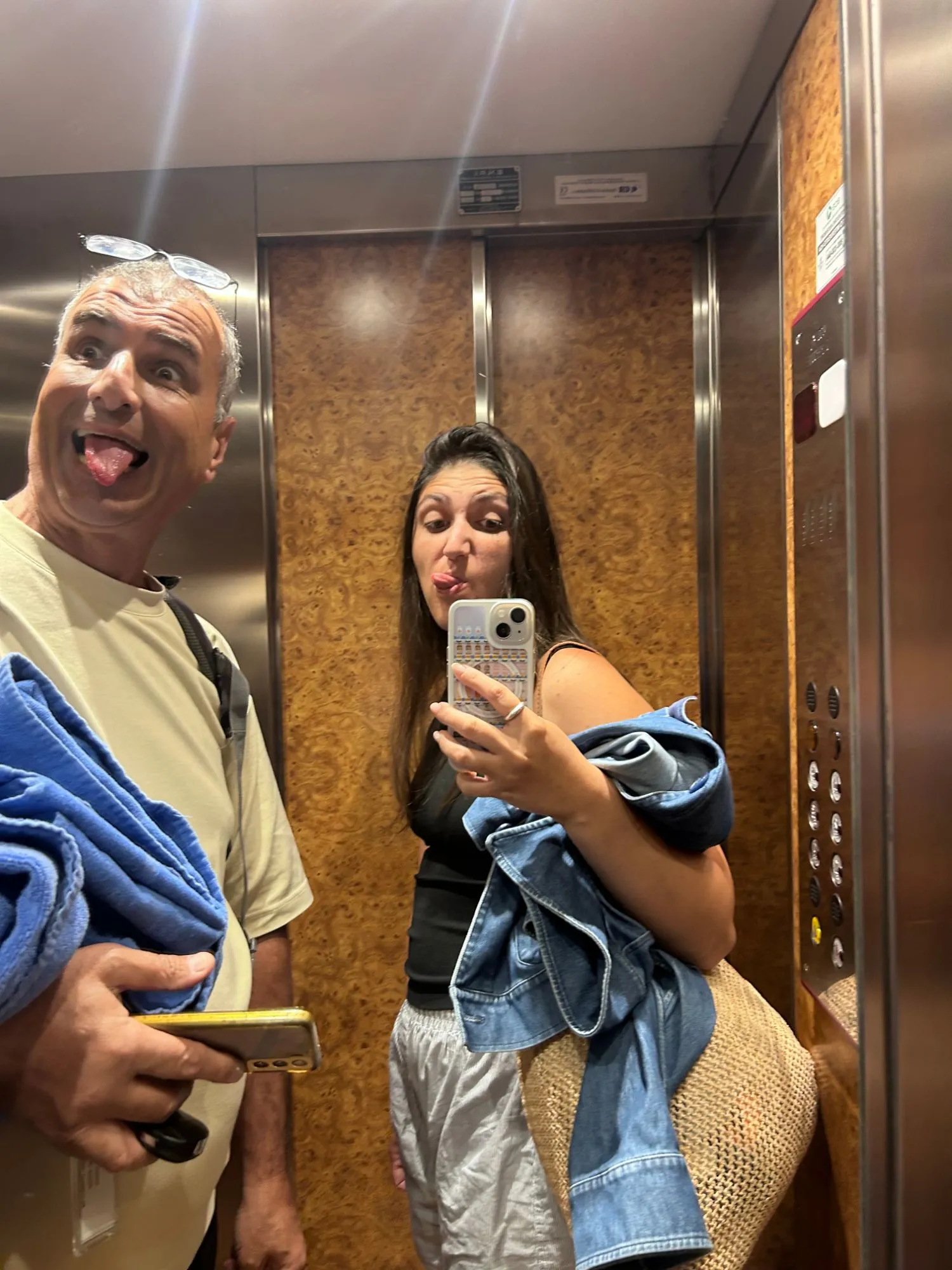 Dana and an older man pulling faces at a lift mirror