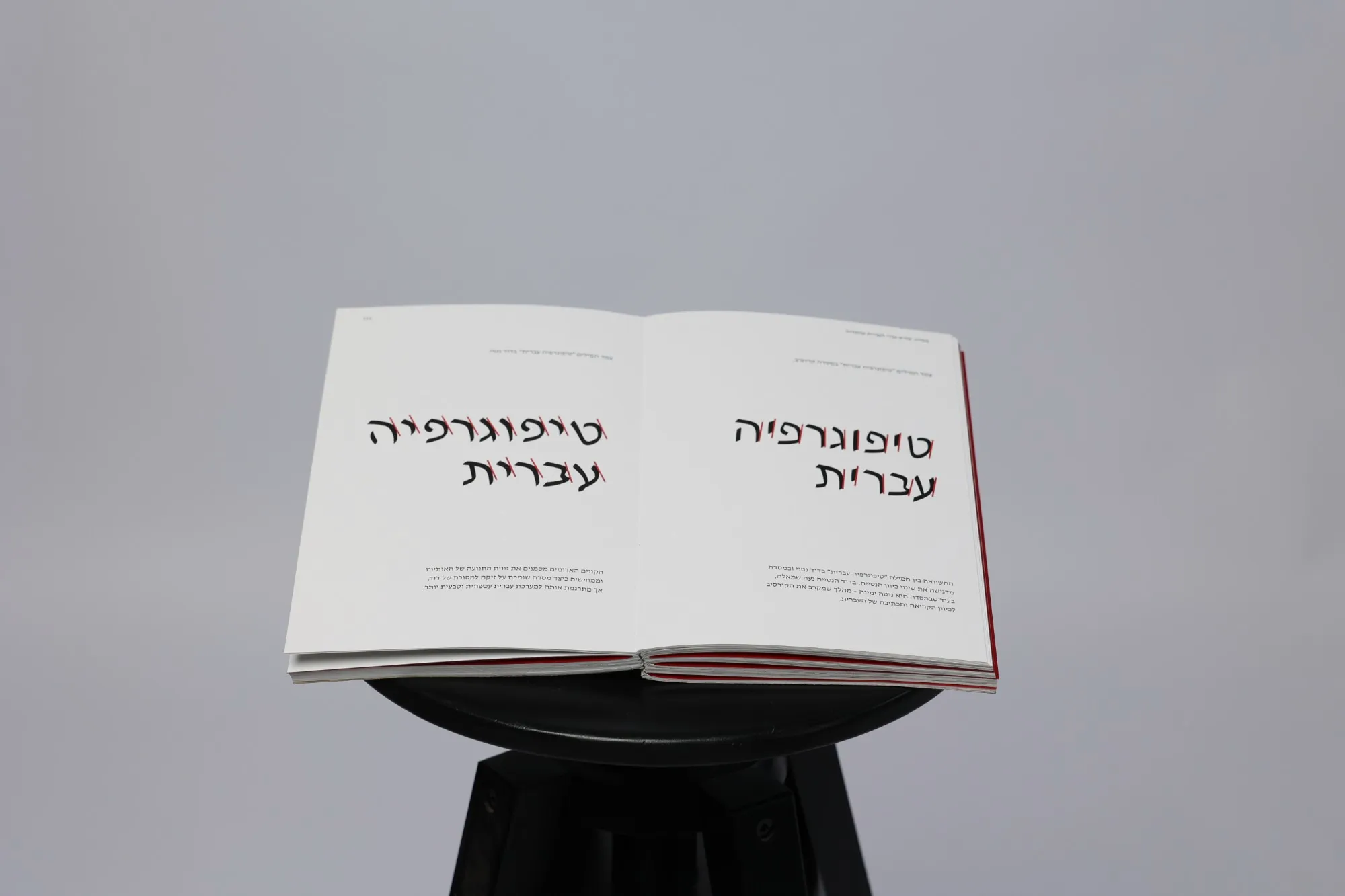 An open spread with the words Hebrew typography set large on both pages, red marks drawn across the letters