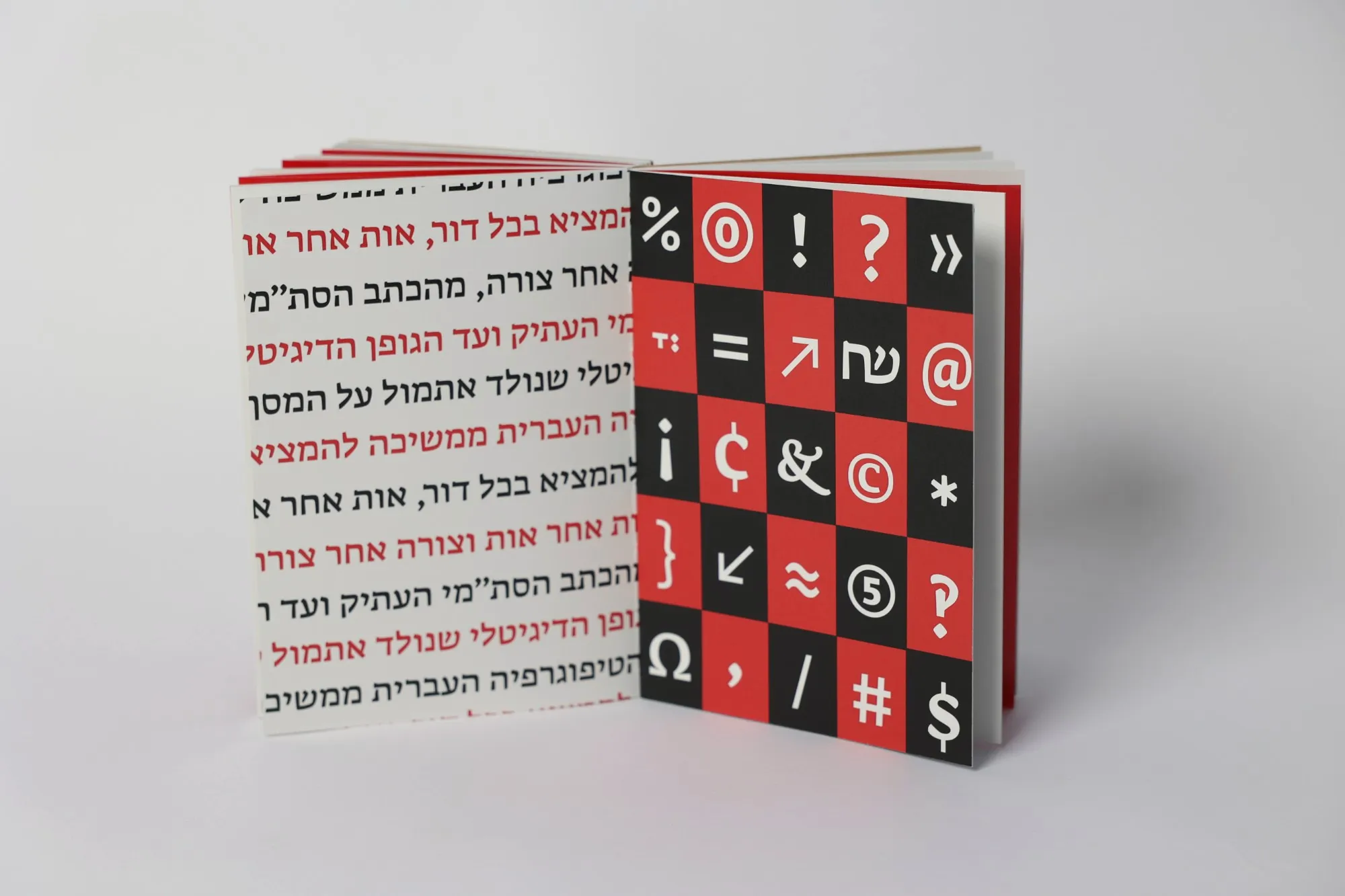 The book held open, a page of running text on the left and a grid of punctuation and symbols in red and black squares on the right